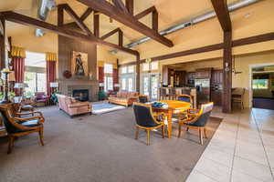 Tiled dining room with beam ceiling, a wealth of natural light, and high vaulted ceiling