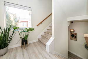 Stairway with a textured ceiling, lofted ceiling, and light hardwood / wood-style floors