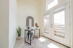 Interior space with a high ceiling, light hardwood / wood-style flooring, and french doors