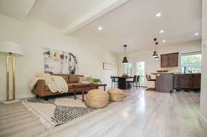 Living room featuring sink, beam ceiling, and light wood-type flooring