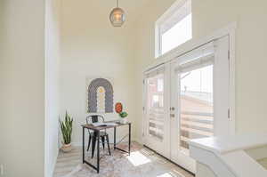 Entryway with a towering ceiling, french doors, and light wood-type flooring