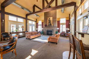 Carpeted living room featuring beam ceiling, a tiled fireplace, french doors, and high vaulted ceiling