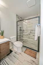 Bathroom with vanity, an enclosed shower, a textured ceiling, and toilet