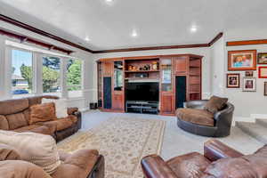 Living room featuring crown molding, carpet, and a textured ceiling