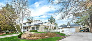 View of property with a garage, an outbuilding, a carport, and covered porch