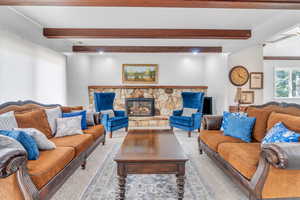 Carpeted living room with a fireplace and beamed ceiling