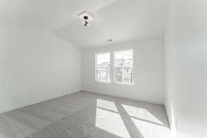 Spare room with vaulted ceiling and light carpet