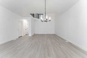 Unfurnished dining area with a chandelier and light hardwood / wood-style flooring