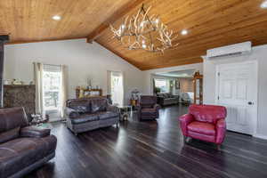 Living room featuring beamed ceiling, an inviting chandelier, a wall mounted air conditioner, high vaulted ceiling, and dark wood-type flooring