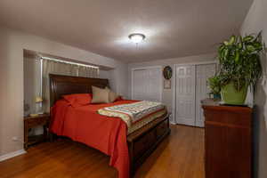 Bedroom featuring two closets, a textured ceiling, and hardwood / wood-style floors