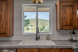 Kitchen with sink, stainless steel dishwasher, and decorative backsplash