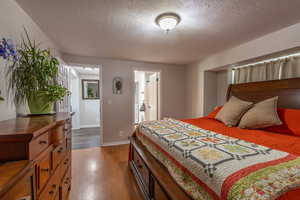 Bedroom with hardwood / wood-style flooring, connected bathroom, and a textured ceiling