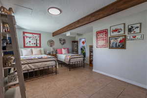 Tiled bedroom with beamed ceiling and a textured ceiling