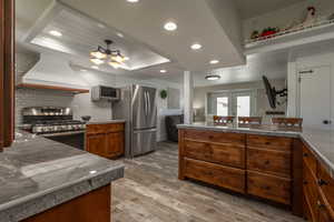 Kitchen featuring appliances with stainless steel finishes, french doors, backsplash, wood-type flooring, and custom range hood