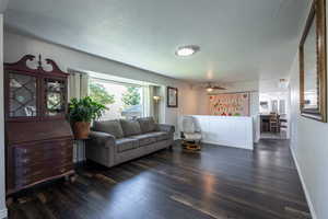 Living room with ceiling fan, a textured ceiling, and dark hardwood / wood-style flooring