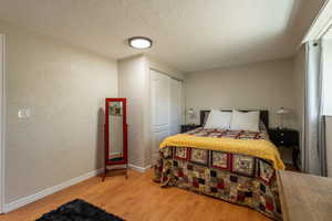 Bedroom with a textured ceiling, hardwood / wood-style flooring, and a closet