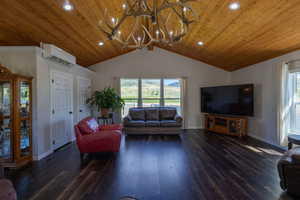 Living room featuring a wall mounted AC, lofted ceiling, a chandelier, wood-type flooring, and ornamental molding