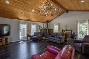 Living room with beamed ceiling, a wood stove, a wealth of natural light, and hardwood / wood-style flooring