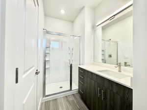 Bathroom with a shower with door, vanity, and hardwood / wood-style floors