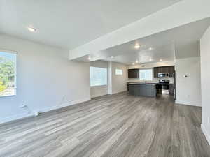 Unfurnished living room featuring sink, a textured ceiling, light hardwood / wood-style flooring, and a healthy amount of sunlight