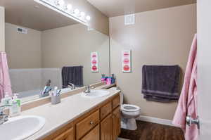 Bathroom featuring double vanity, hardwood / wood-style flooring, a bath, and toilet