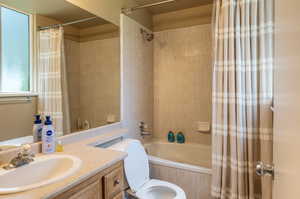 Full bathroom with vanity, shower / tub combo, and toilet