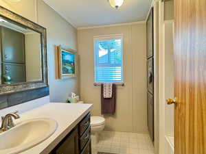 Bathroom with vanity, toilet, tile patterned floors, and crown molding