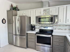 Kitchen featuring appliances with stainless steel finishes, tasteful backsplash, lofted ceiling, and gray cabinets