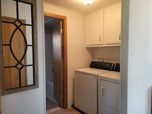 Laundry room featuring washer and clothes dryer and cabinets