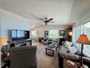 Living room with a textured ceiling, vaulted ceiling, carpet floors, and ceiling fan