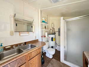 Bathroom with electric water heater, tile walls, toilet, and tile patterned floors