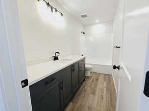 Full bathroom with hardwood / wood-style flooring, shower / bath combination, toilet, and vanity