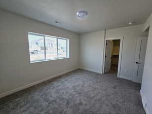 Unfurnished bedroom with carpet flooring, a textured ceiling, a closet, and a spacious closet