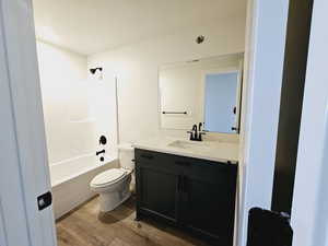 Full bathroom with wood-type flooring, toilet, shower / bathtub combination, and vanity