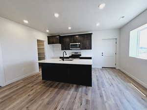 Kitchen featuring sink, light hardwood / wood-style flooring, range, and an island with sink