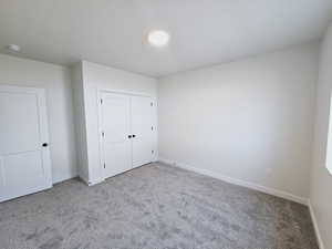 Unfurnished bedroom with a closet and light colored carpet