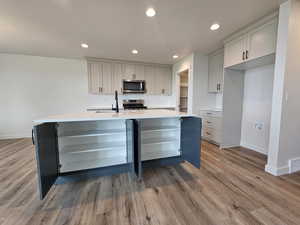 Kitchen featuring range, sink, a kitchen island with sink, and light hardwood / wood-style floors