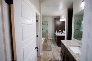 Bathroom featuring a stall shower, two vanities, and a sink