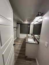 Bathroom featuring toilet, wood finished floors, vanity, baseboards, and shower / tub combo
