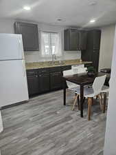 Kitchen featuring light stone counters, light wood-type flooring, white appliances, and sink