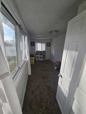 Interior space featuring dark colored carpet, a textured ceiling, and plenty of natural light