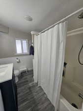 Full bathroom with shower / bathtub combination with curtain, hardwood / wood-style floors, a textured ceiling, toilet, and vanity