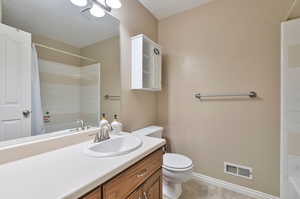 Full bathroom with shower / bathtub combination with curtain, vanity, tile patterned floors, and toilet