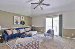 Carpeted living room featuring ceiling fan