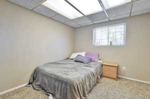 Carpeted bedroom featuring a drop ceiling