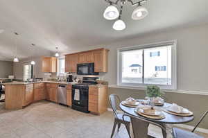 Kitchen with light tile patterned flooring, kitchen peninsula, hanging light fixtures, and black appliances