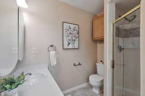 Bathroom with a shower with door, tile patterned floors, vanity, and toilet