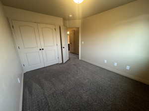 Unfurnished bedroom featuring a closet and dark carpet