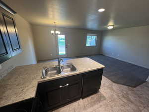 Kitchen featuring light tile patterned floors, an inviting chandelier, hanging light fixtures, black dishwasher, and sink