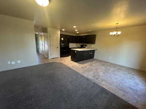 Kitchen with sink, hanging light fixtures, black fridge with ice dispenser, a chandelier, and light carpet